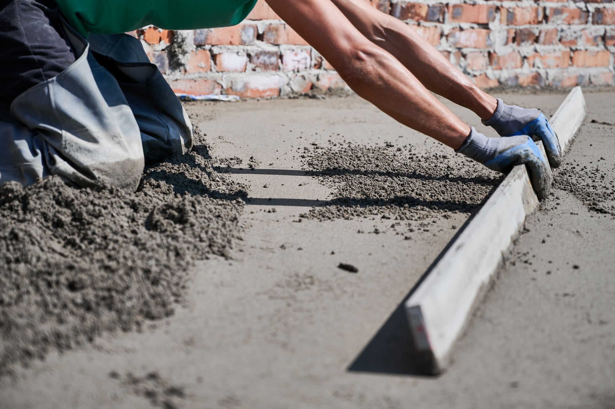 Male builder screeding floor at construction site.